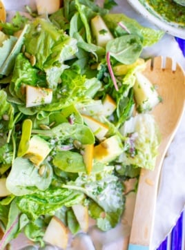 baby kale salad with a wooden spoon