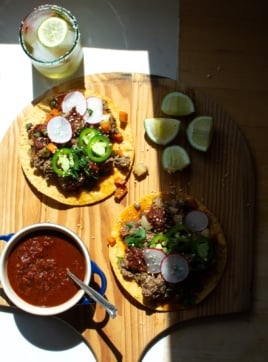 Picadillo tostadas on a cutting board with salsa