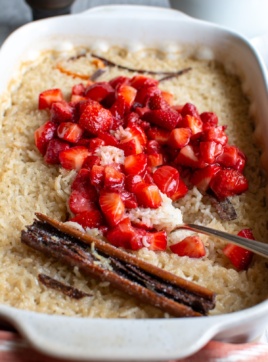 A baking dish of arroz con leche with strawberries on top.