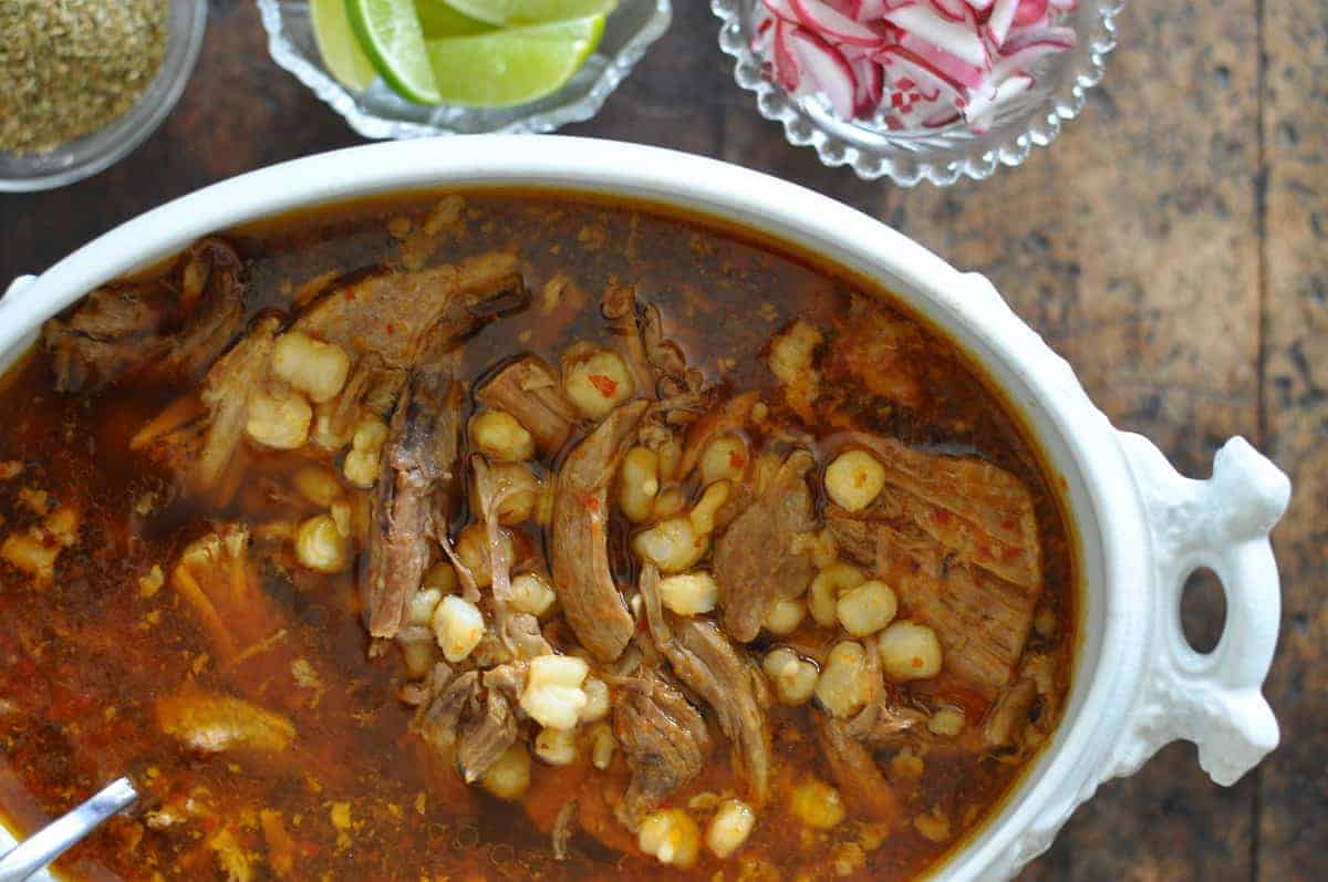 A classic Pozole Rojo recipe with tender pork, hominy, and red chile broth. Top the stew with sliced radishes, dried oregano, and chopped onion. Dairy-free!