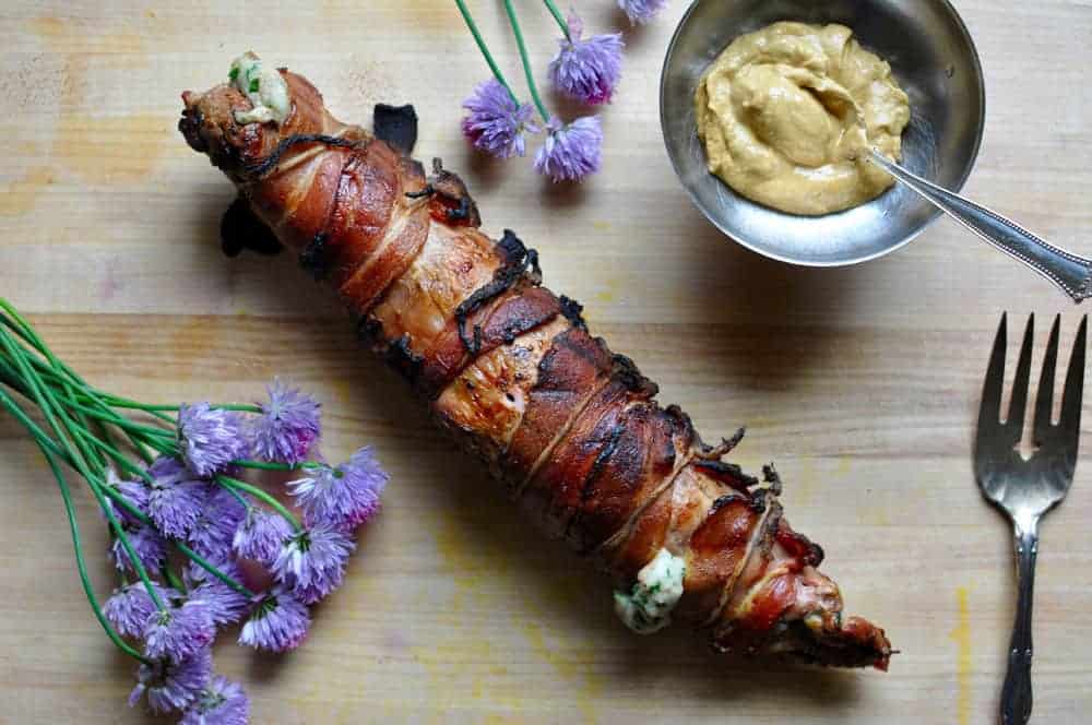 This grilled Cotija Stuffed Pork Tenderloin wrapped in bacon and brushed with mustard is the most surefire way to impress your guests this grilling season. #porktenderloin #grilledporktenderloin #stuffedporktenderloin #baconwrappedpork