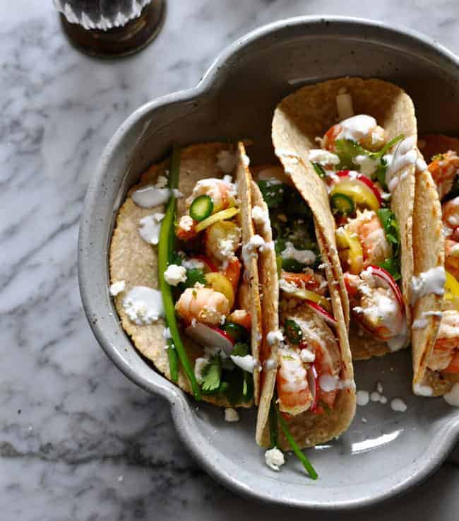 These weeknight shrimp tacos are marinated in garlic and black pepper. Dress them up with as many garnishes as you'd like for an easy weeknight dinner.