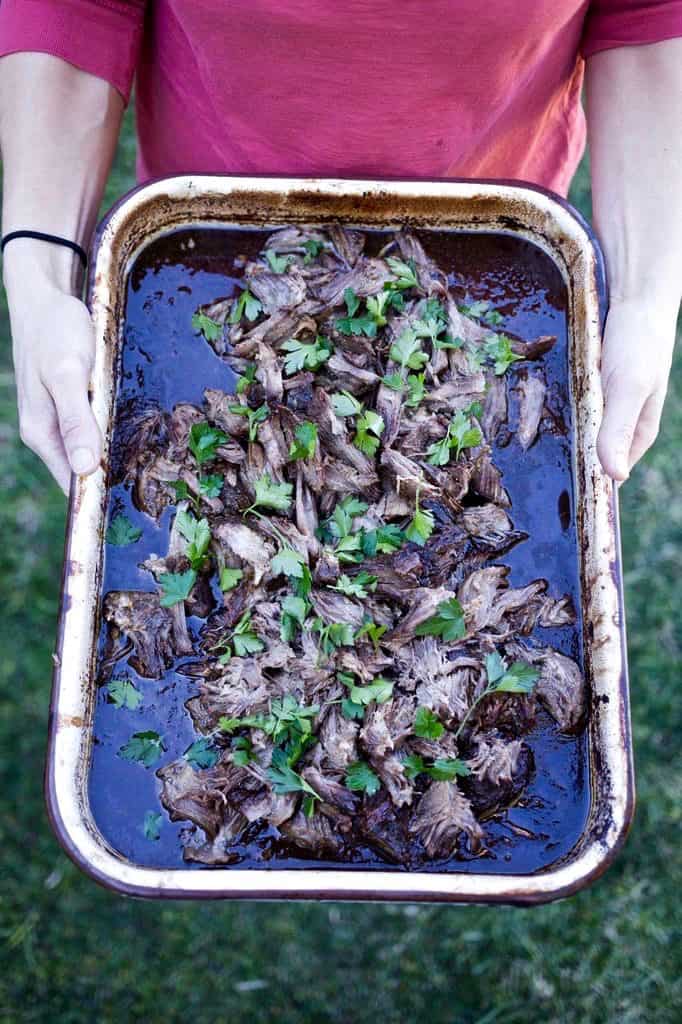 barbacoa in a metal dish being held by a woman.