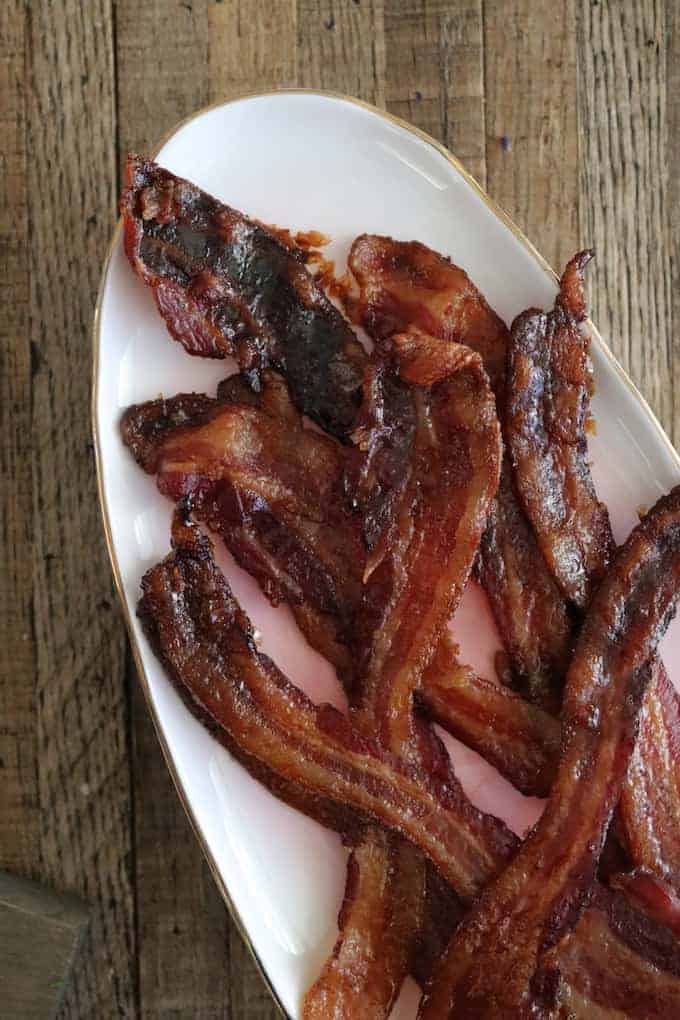 Tequila brown sugar bacon is God's gift to bacon. Dark anejo tequila and dark brown sugar coat this oven-baked bacon and create crisp, caramelized strips of smoky bacon. #bacon #ovenbacon #baconcandy