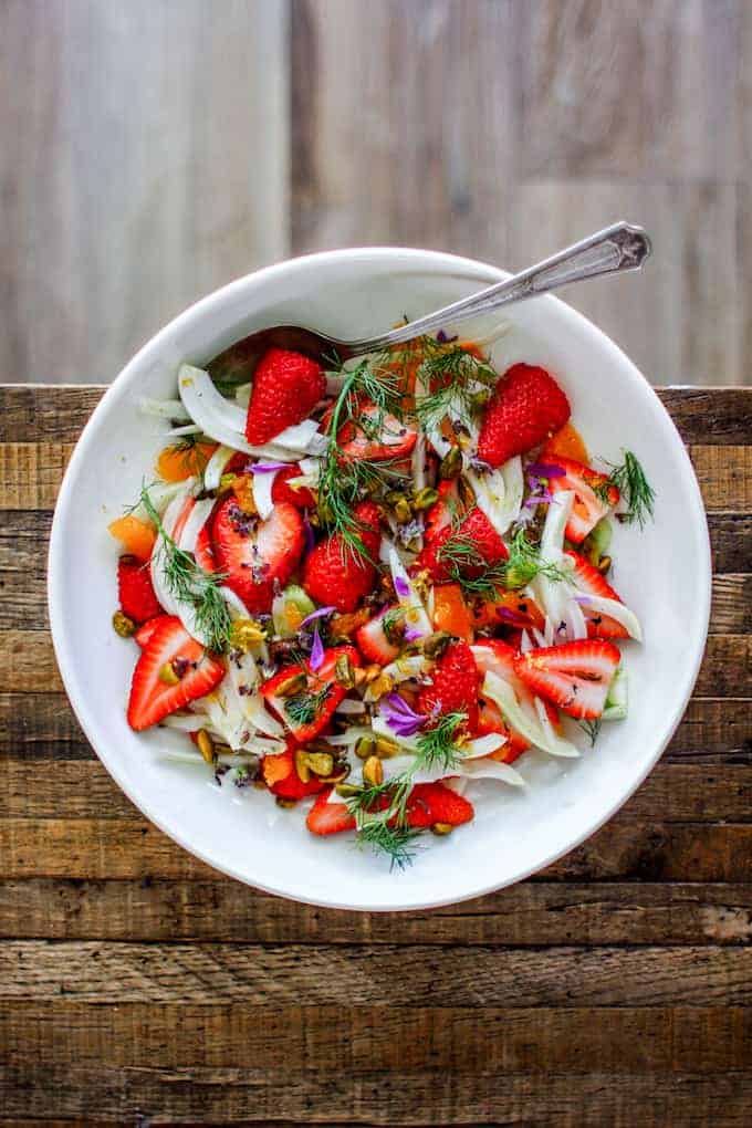 This winter fruit salad is a gorgeous combination of thinly sliced fennel, juicy strawberries, and floral clementines tossed in a lemon and honey dressing and sprinkled with roasted pistachios. #fruitsalad #brunchrecipe #fruitsaladrecipe
