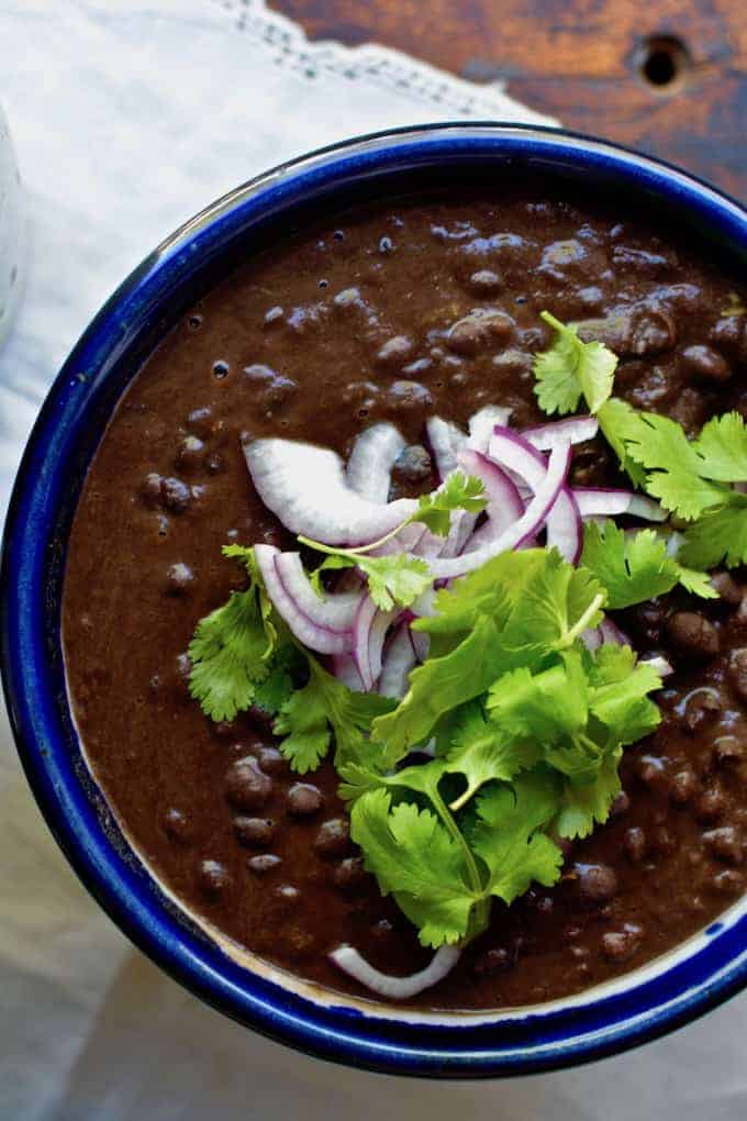 A bowl of black beans with cilantro and onions on top.