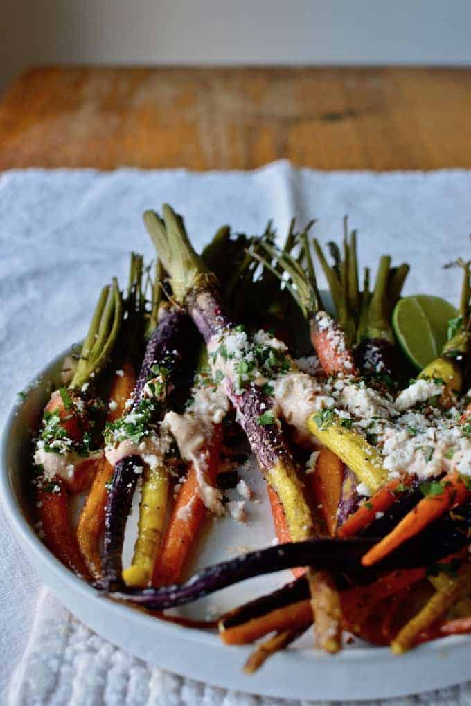 These Roasted Mexican Street Carrots are just like everyone's favorite street corn with cotija cheese, cilantro, and a creamy roasted garlic-lime dressing. Make for a quick and easy holiday side. Goes great with turkey, beef tenderloin, or ham. #roastcarrots #vegetarian #holidayside #easyside #carrots #Mexican #thanksgiving #roastedcarrots