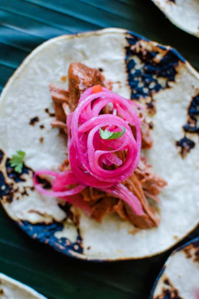 Cochinita Pibil pork tacos topped with spicy pickled red onions. 