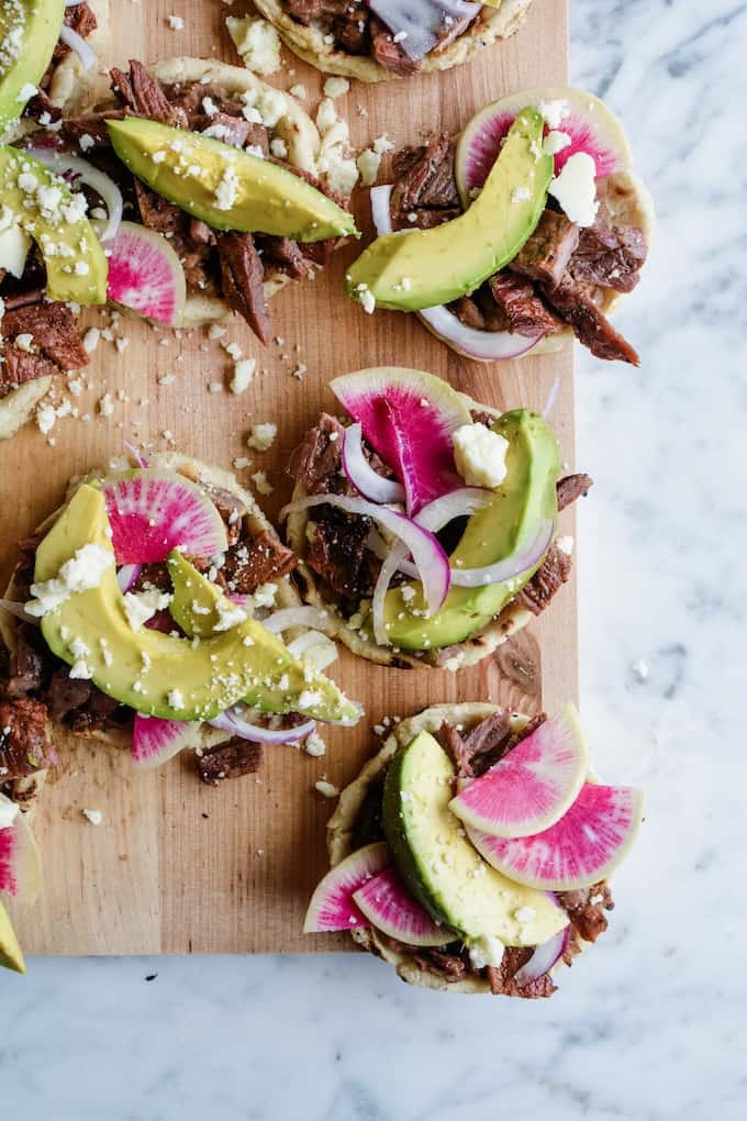 Everything you need to know about making the BEST Mexican sopes! This easy sopes recipe is topped with grilled carne asada, ripe avocado, and queso fresco. #sopes #holajalapeno #Mexicansopes #howtomakesopes #sopesrecipe