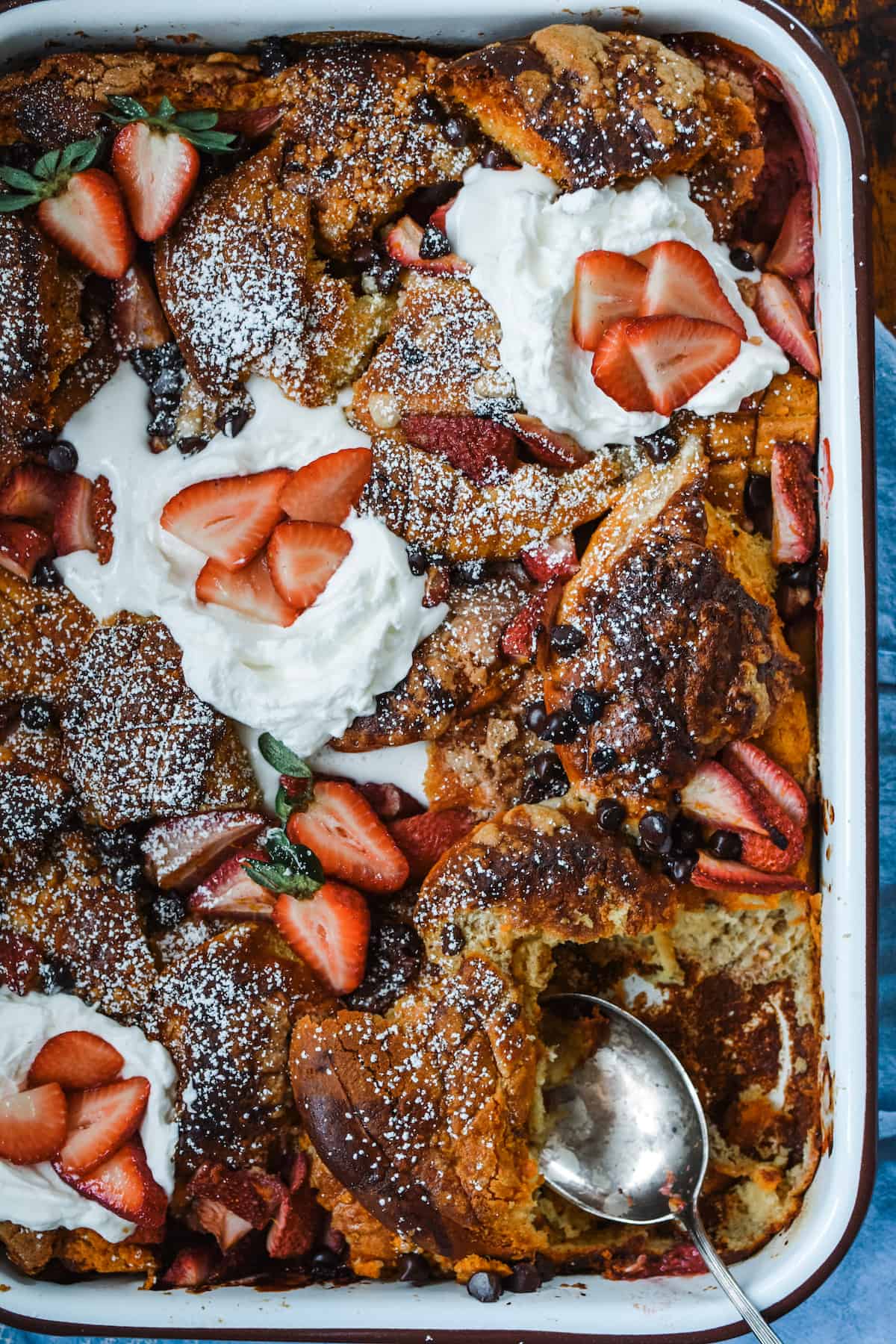 This totally indulgent French Toast Casserole is made with Conchas, the traditional Mexican sweet bread and soaked in a classic tres leches mixture of sweetened condensed milk, whole milk, and heavy cream. If that wasn't enough it then gets topped with chocolate chips, orange-scented strawberries, and whipped cream. Assemble the night before for an outrageously good breakfast the next morning! #frenchtoastcasserole #bakedfrenchtoast #tresleches #conchas