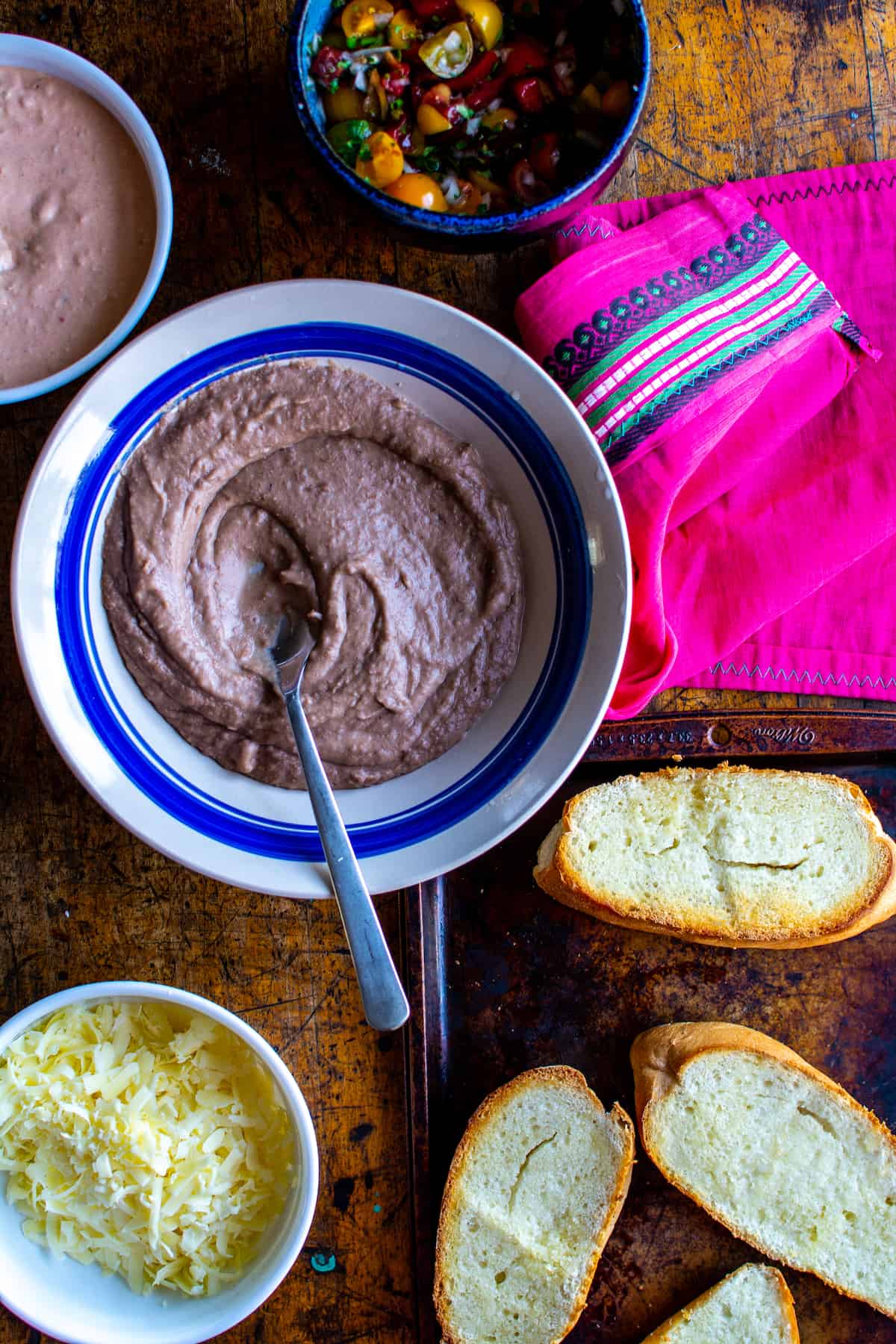A dish of refried beans next to bread pieces