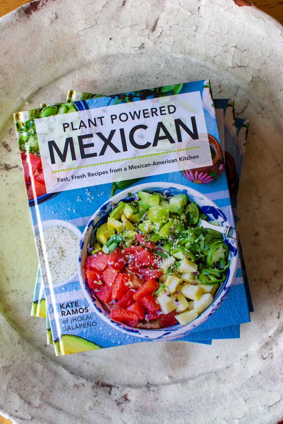 Plant Powered Mexican cookbook sitting on a white ceramic bowl.