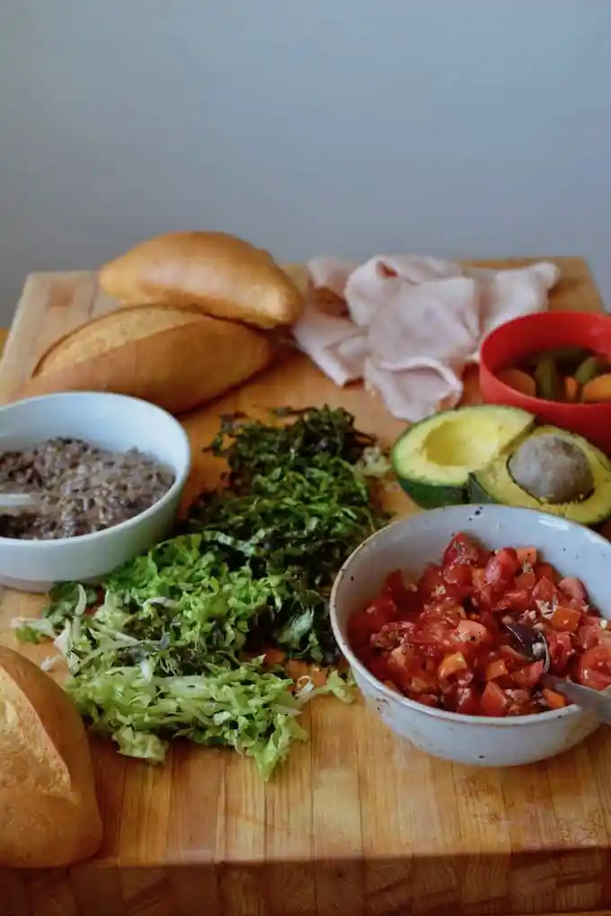 A cutting board with all the fixings to make Tortas including shredded lettuce and more.