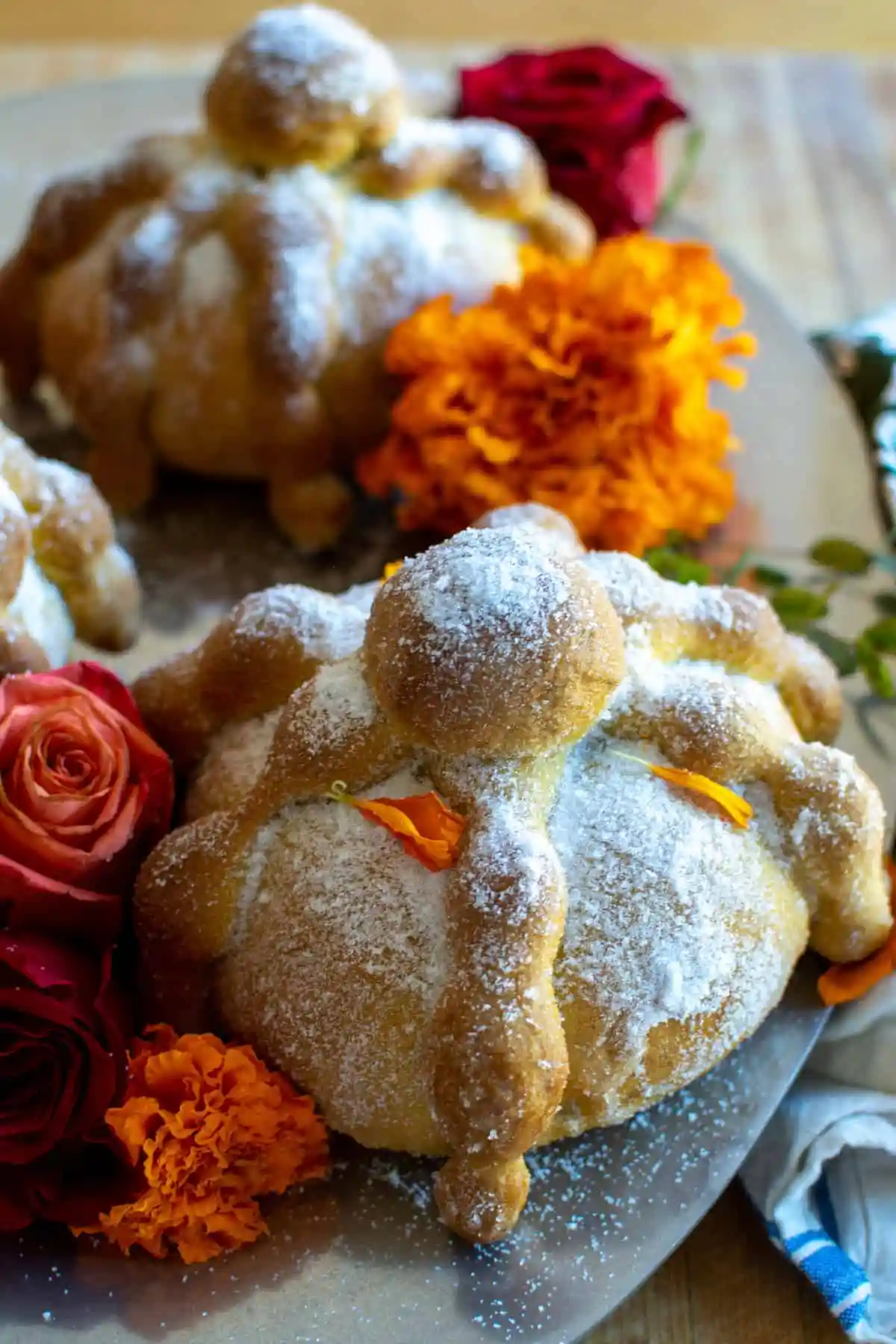 A plate of pan de muerto surrounded by flowers.