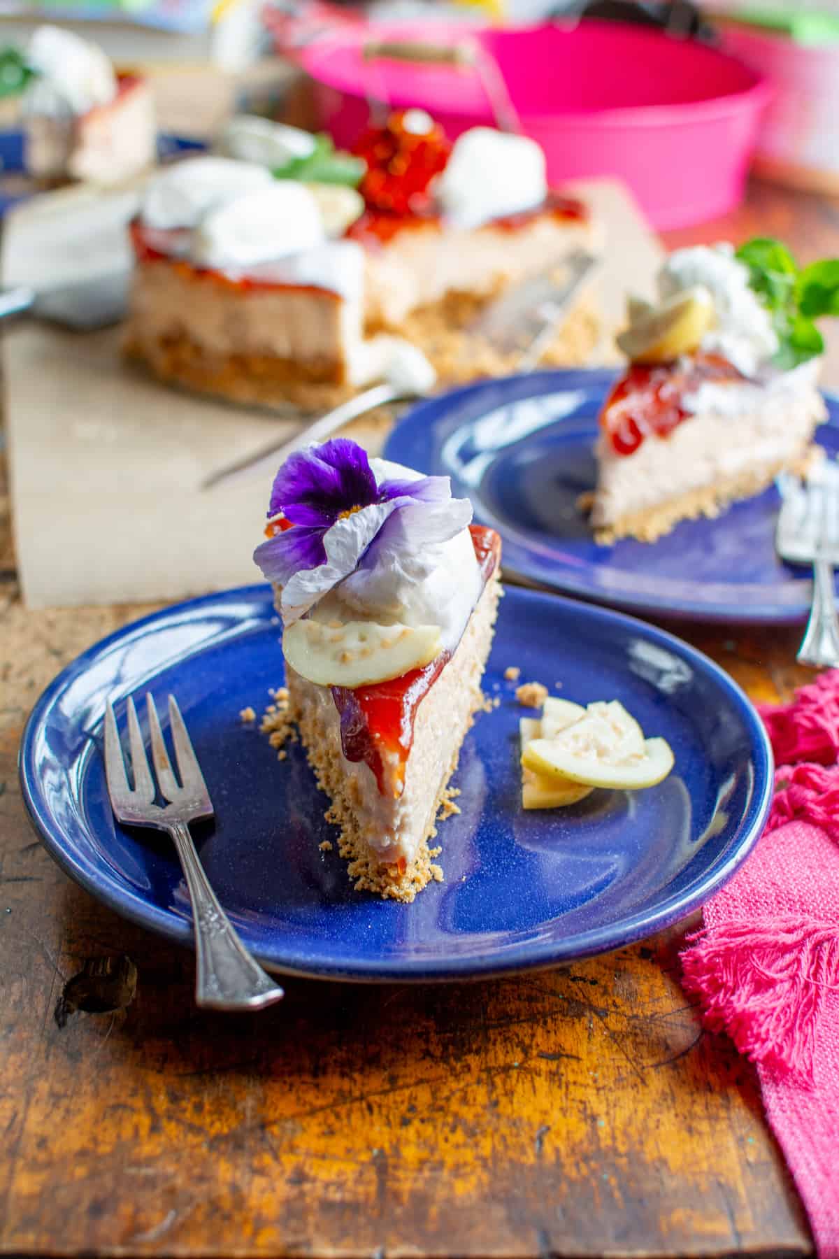 A slice of guava cheesecake on a blue plate with a fork on the plate.