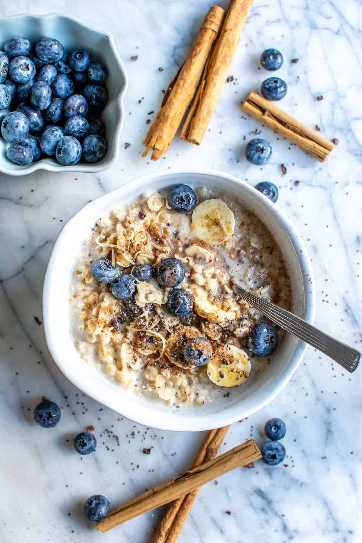 Mexican avena in a white bowl with cinnamon sticks and blueberries