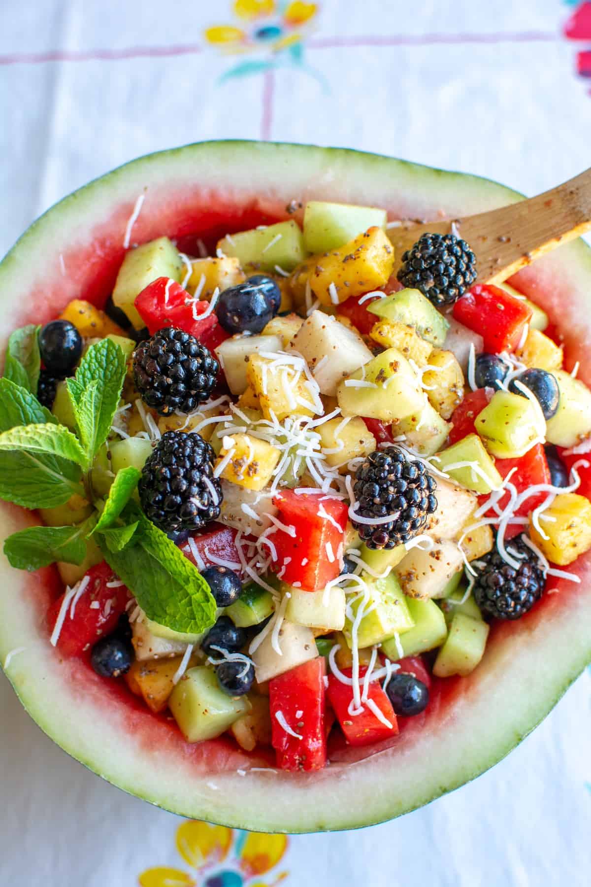 Mexican fruit salad in a half of a watermelon with a spoon in it.