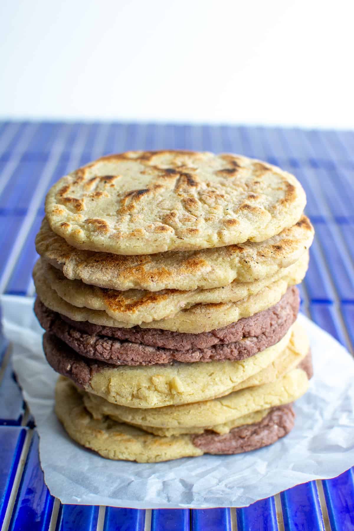 A tall stack of gorditas de maíz on a blue table.