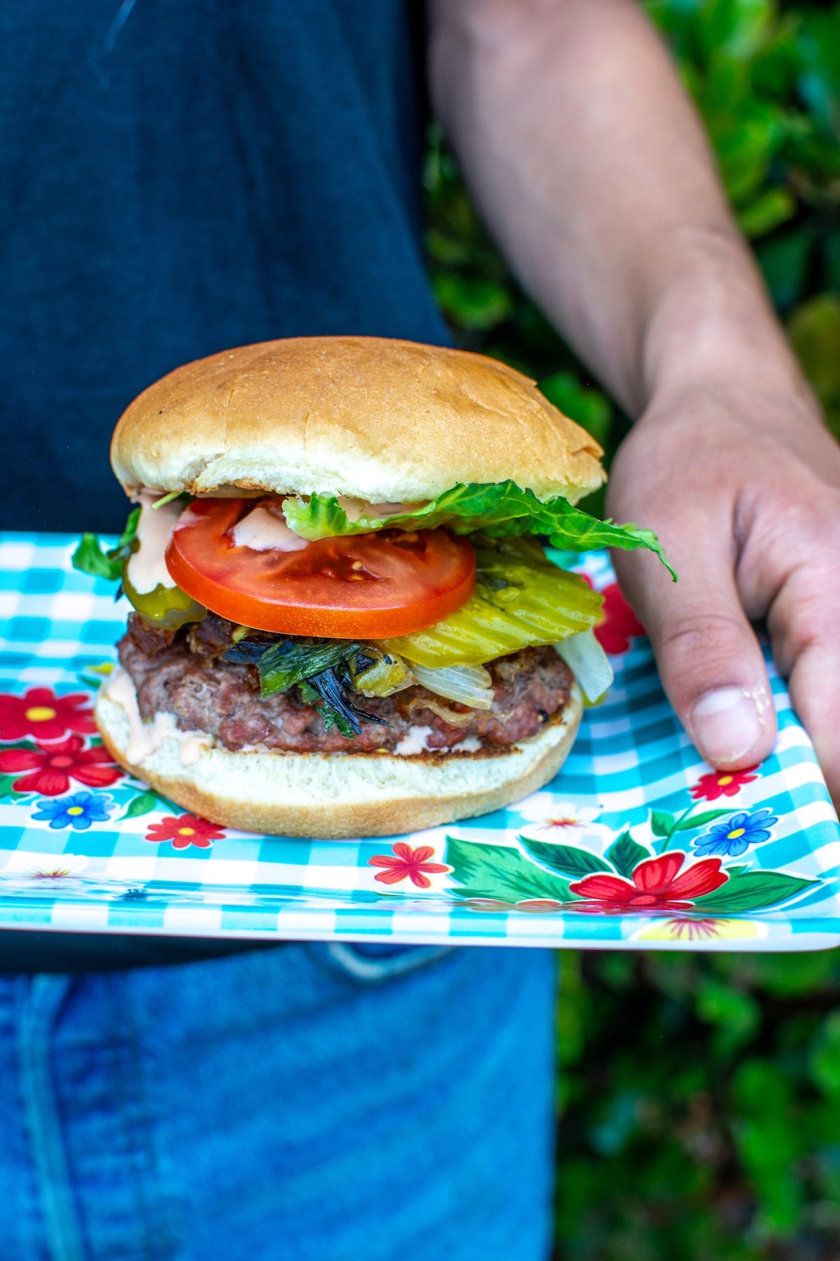 A boy holding a tray of burgers