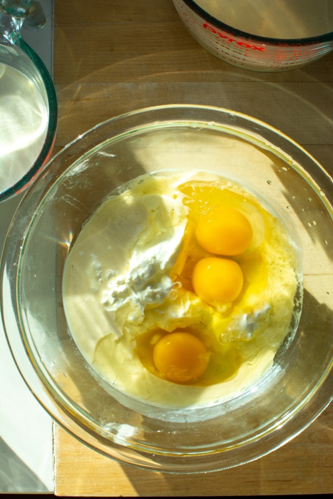 Eggs, sour cream, and eggnog in a glass bowl
