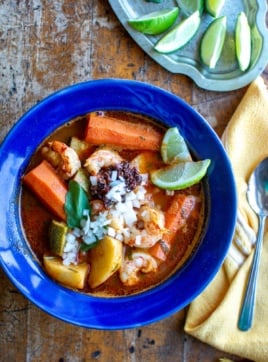 A bowl of Caldo de Camarón topped with fresh lime wedges
