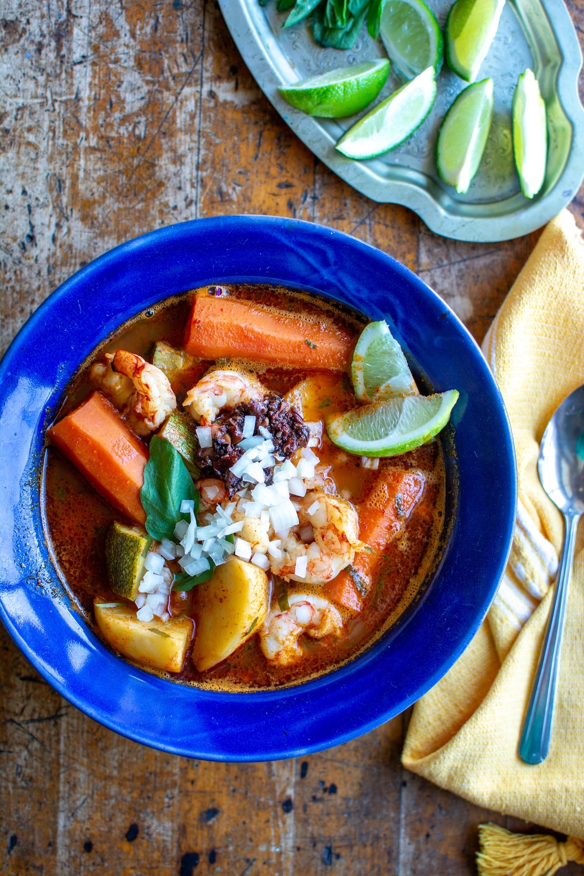 A bowl of Caldo de Camarón topped with fresh lime wedges