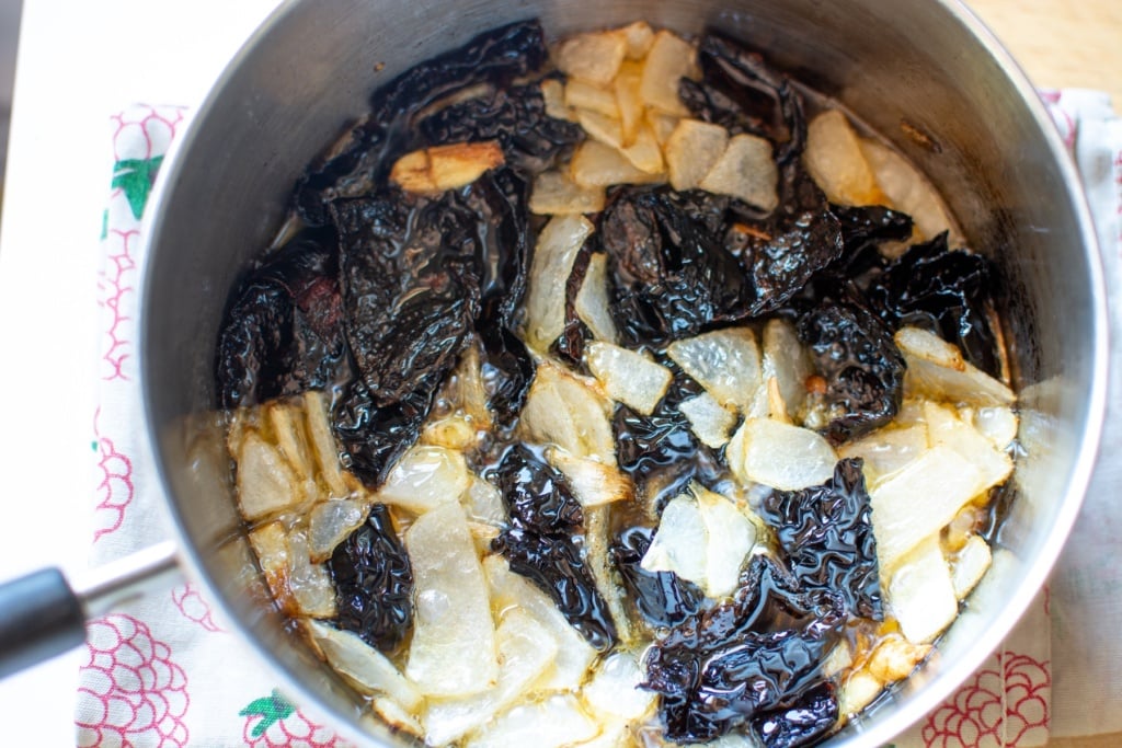 Adding the chiles to the oil in a saucepan. 