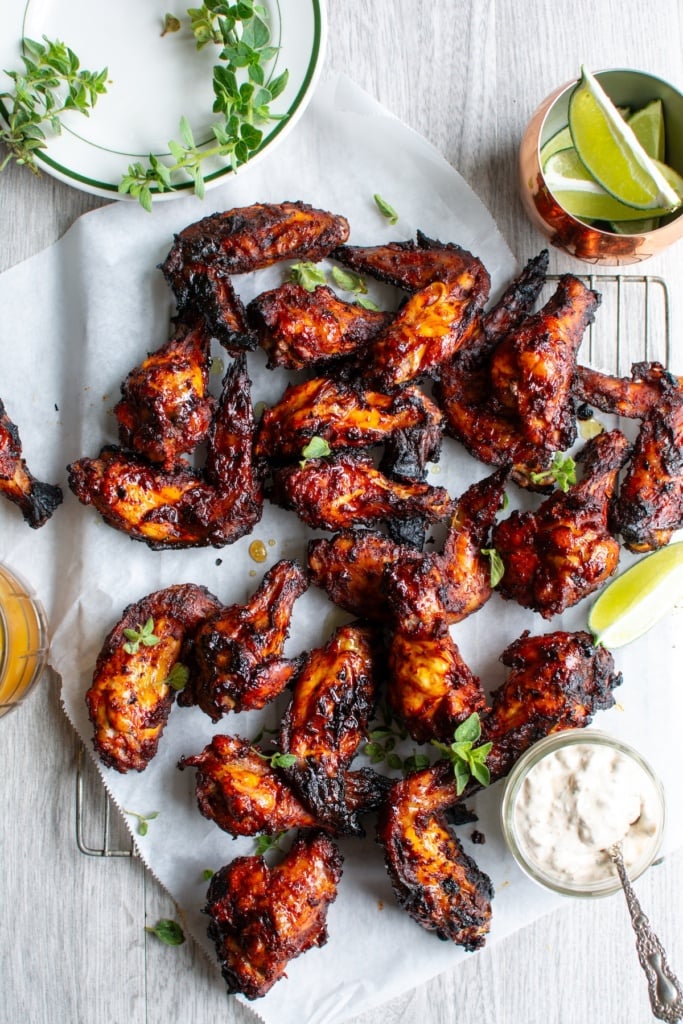 al pastor chicken wings on a table with lime wedges and sauce 