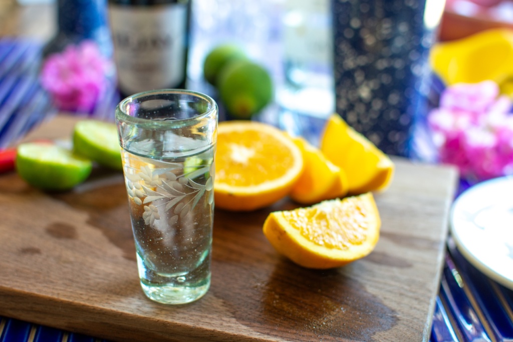 a shot of tequila next to oranges