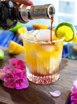 a morning margarita with a hand pouring creme de cassis in the glass