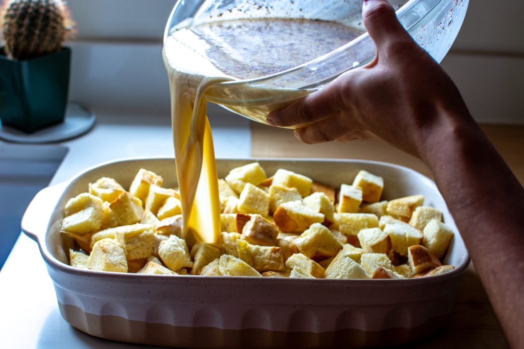 custard being poured over the bread cubes