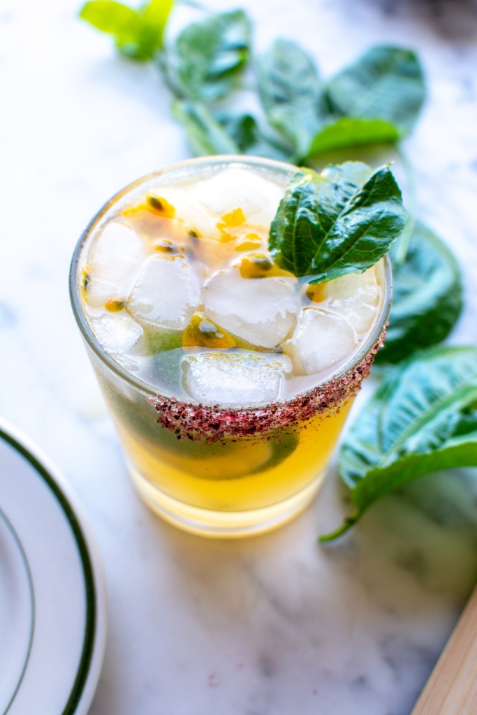 A passion fruit margarita next to passion fruit leaves