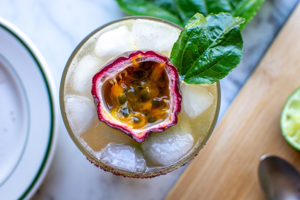 A margarita with a passion fruit half on top