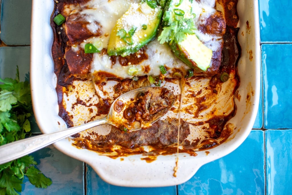 A baking dish of enchiladas with two enchiladas missing