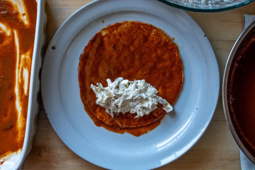 The chicken filling on top of a corn tortilla dipped in sauce. 