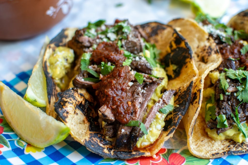 Barbacoa tacos with a lime wedge next to it. 