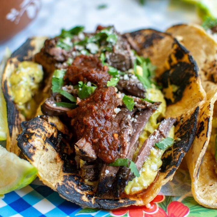 Barbacoa tacos with a lime wedge next to it.