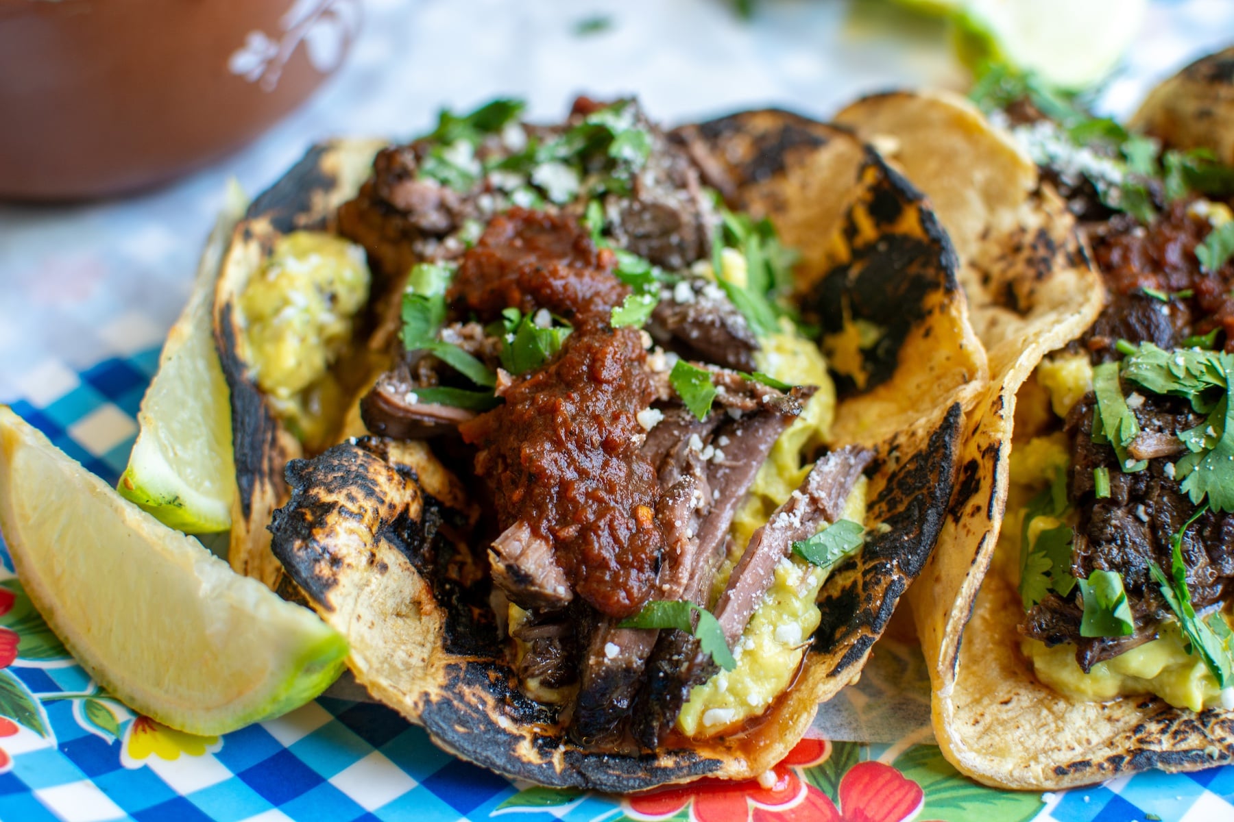 Barbacoa tacos with a lime wedge next to it.