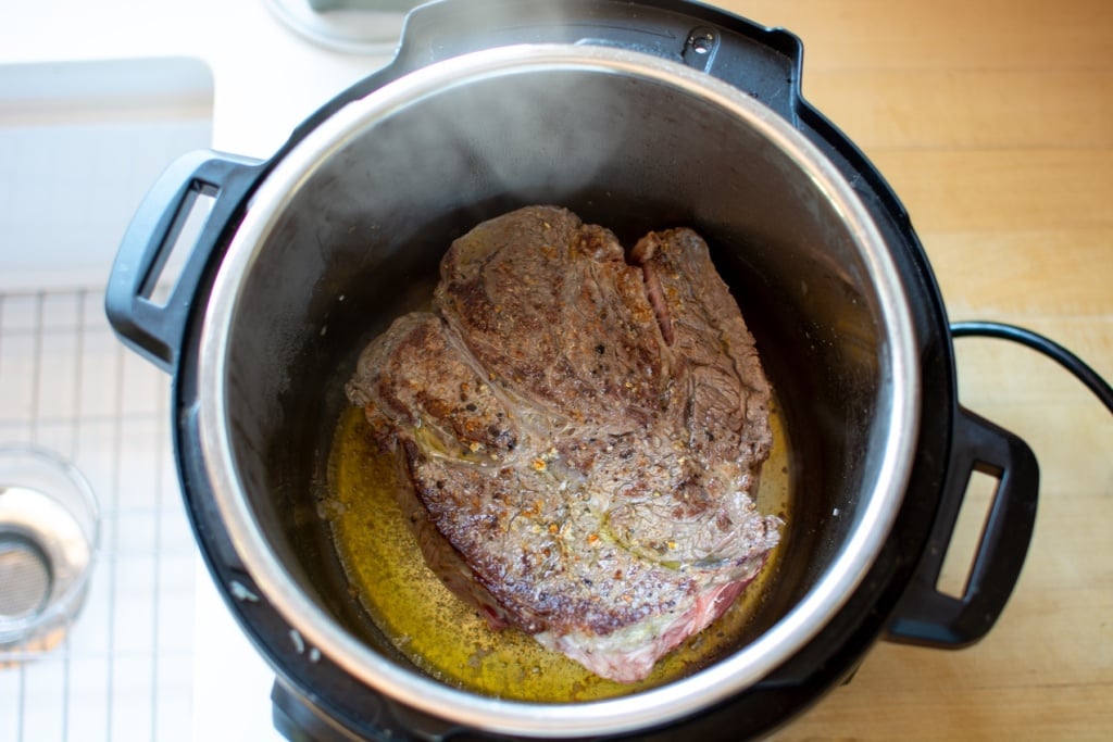 A chuck roast searing in an Instant Pot