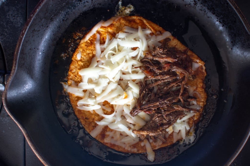 a tortilla covered in cheese and half with meat