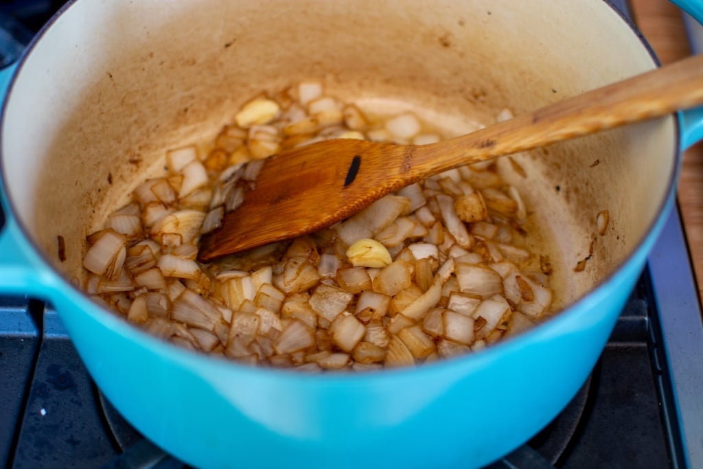 onions and garlic sautéing in a blue pot