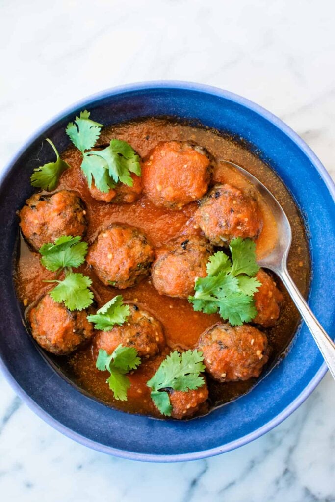 a blue dish of meatballs with chili sauce on top