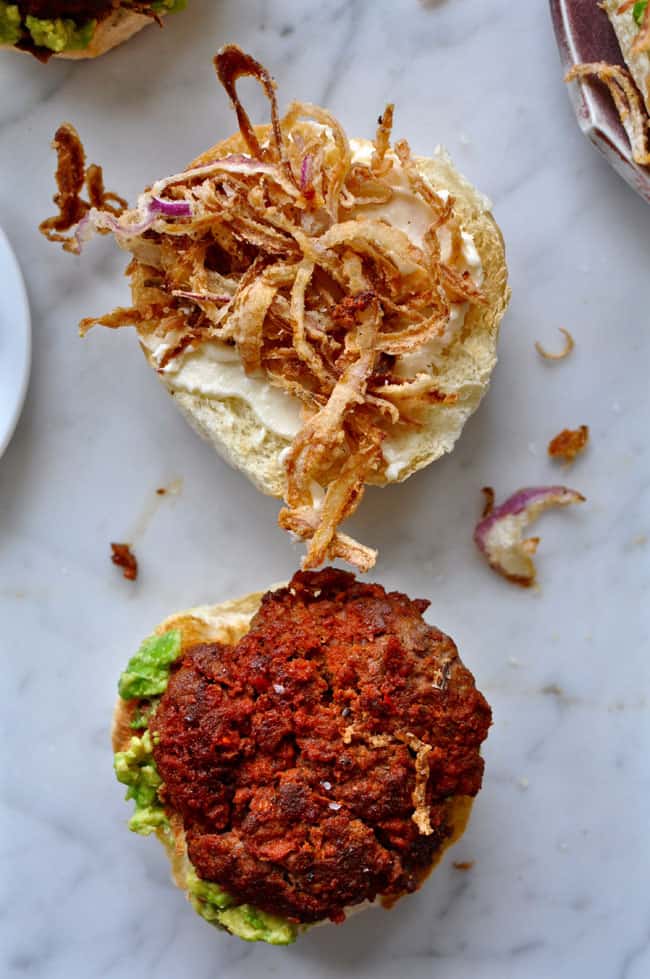 a burger on a bun with another bun with crispy onions