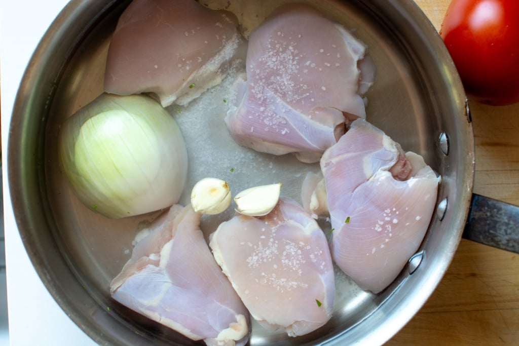 chicken thighs and white onion, salt in a pot with water