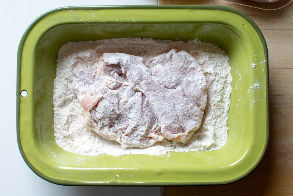 chicken coated in breading mixture in a shallow green dish