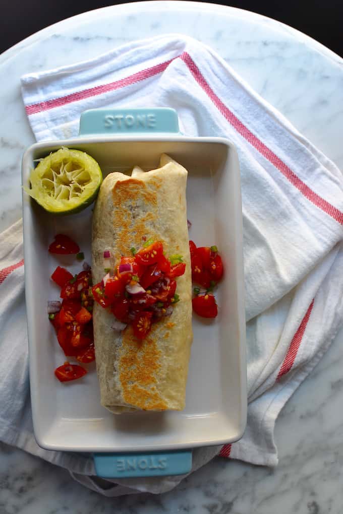 a burrito in a dish topped with salsa