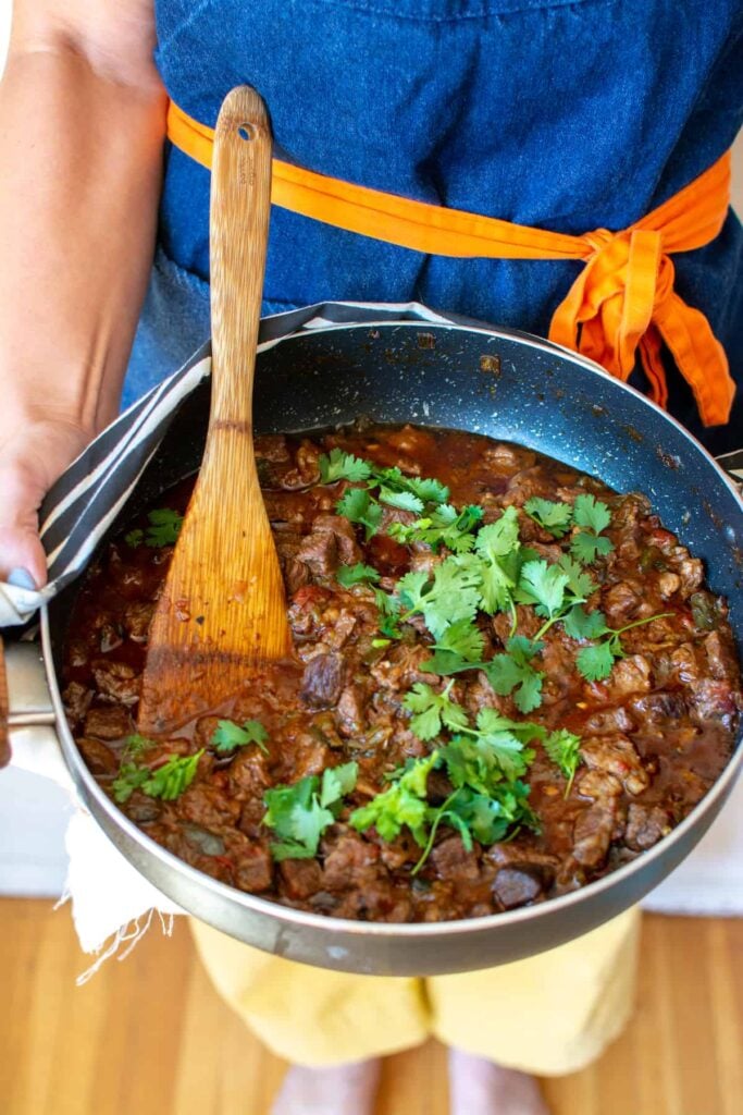 a woman holding a pot of beef