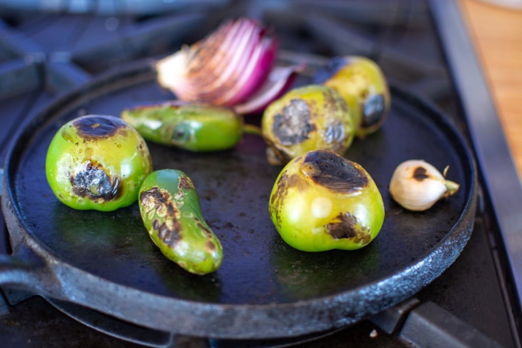 peppers, onions, tomatillos and garlic on a comal