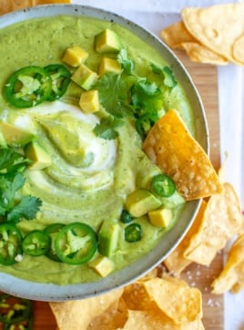 a bowl of salsa de aguacate with a chip in it