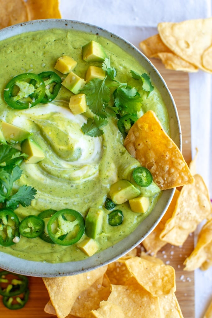 a bowl of salsa de aguacate with a chip in it